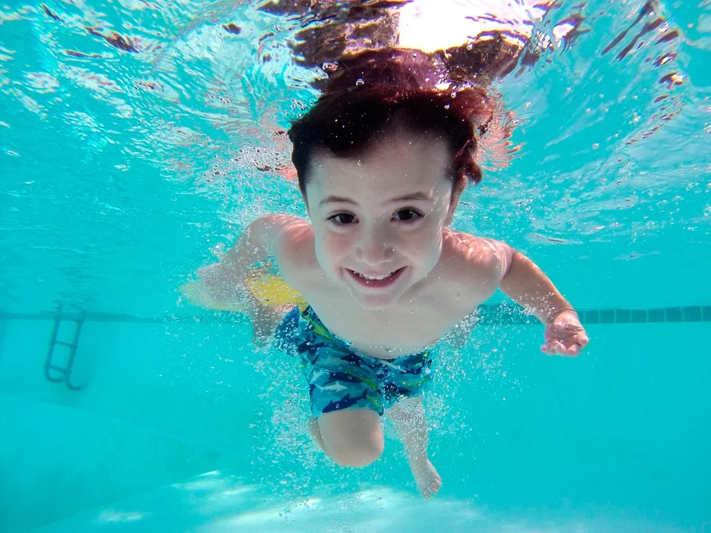 Niño jugando búsqueda del tesoro en la piscina
