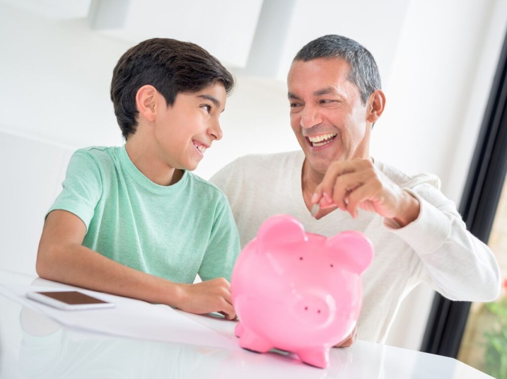 Niño ahorrando con su padre, en un cochinito