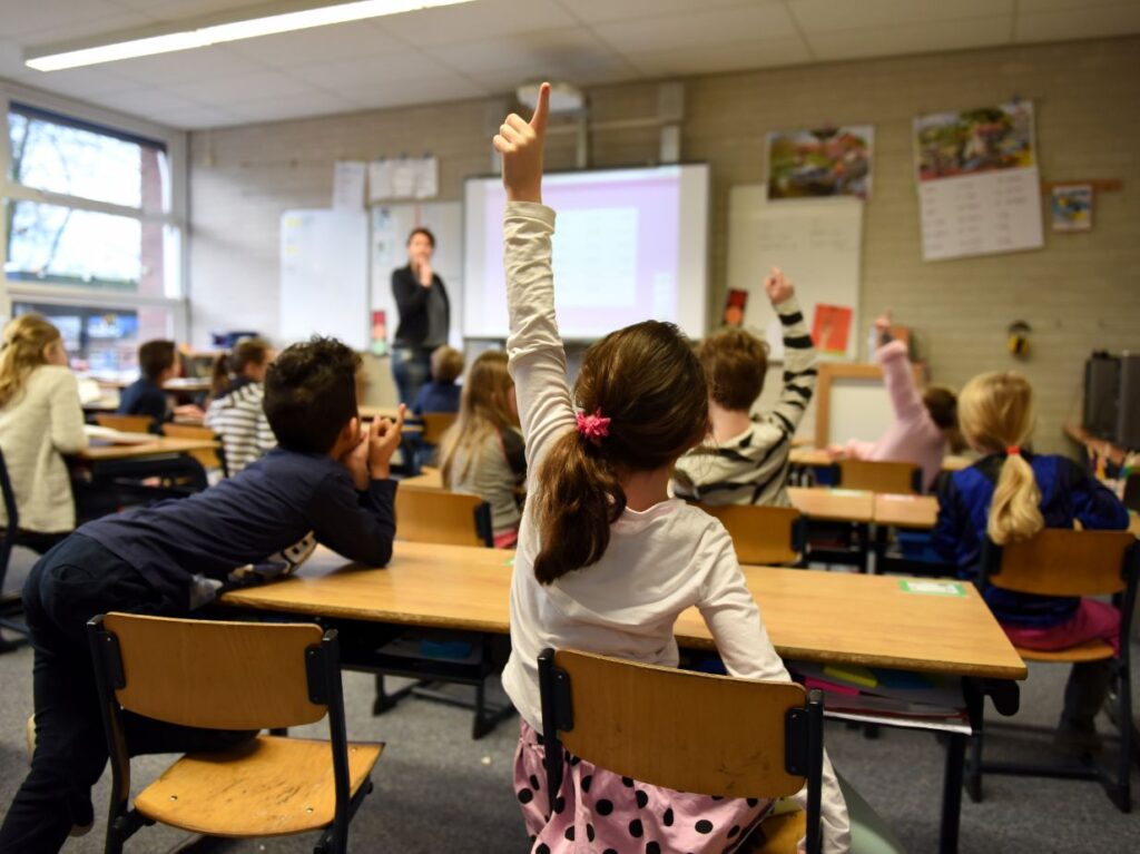 Grupo de niños participando en un salón de clases, tras el regreso de vacaciones de verano