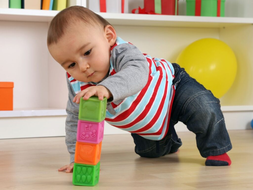 Niño colocando un cubo arriba de otro, lo que representa un ejercicio de estimulación temprana para bebés