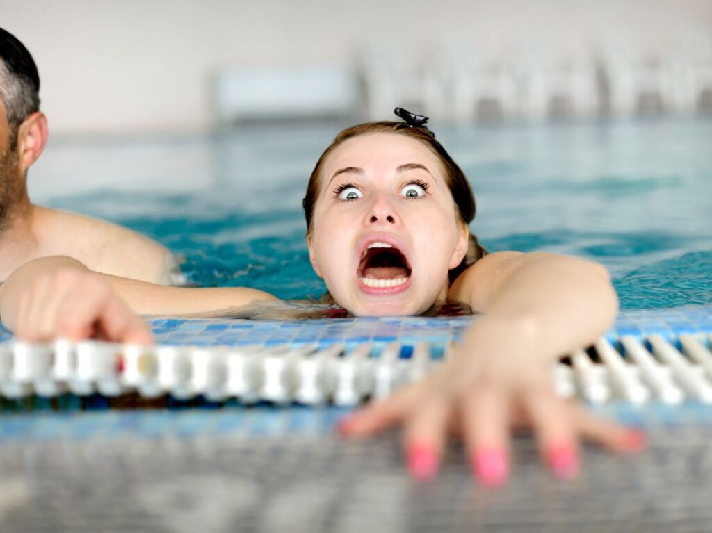 Mujer gritando en el borde de una piscina, por su miedo al agua