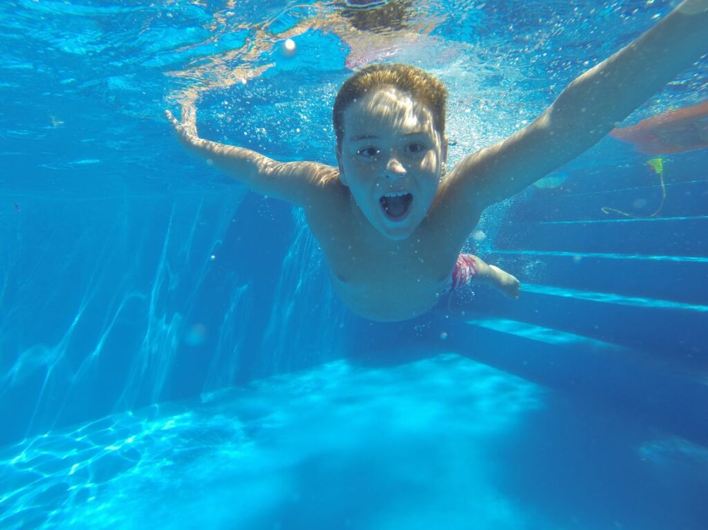 Un niño tomando clases de natación para niños con miedo al agua, sumergido en una piscina