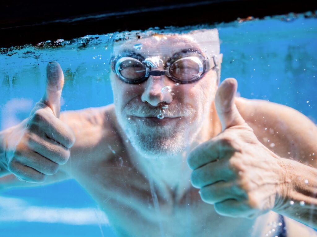 Señor abajo del agua, nadando y disfrutando de los beneficios de la natación para adultos mayores con artritis