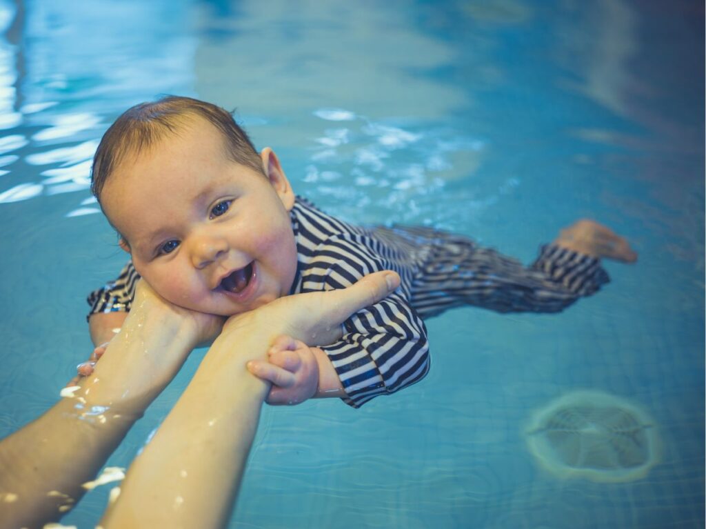Bebé nadando y disfrutando de una clases de natación para bebés con papás