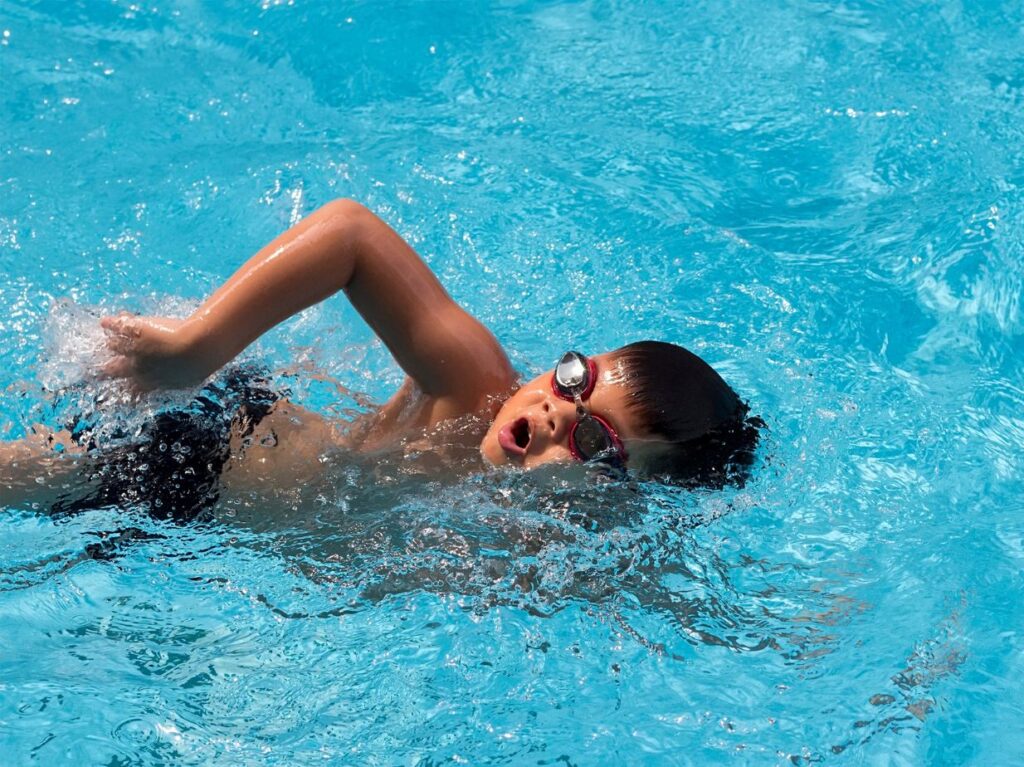 Niño nadando como profesional en una piscina
