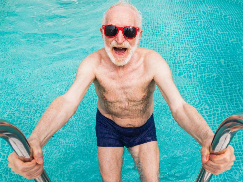 Un señor saliendo de una piscina y preguntándose cómo mejora la movilidad en adultos mayores con natación