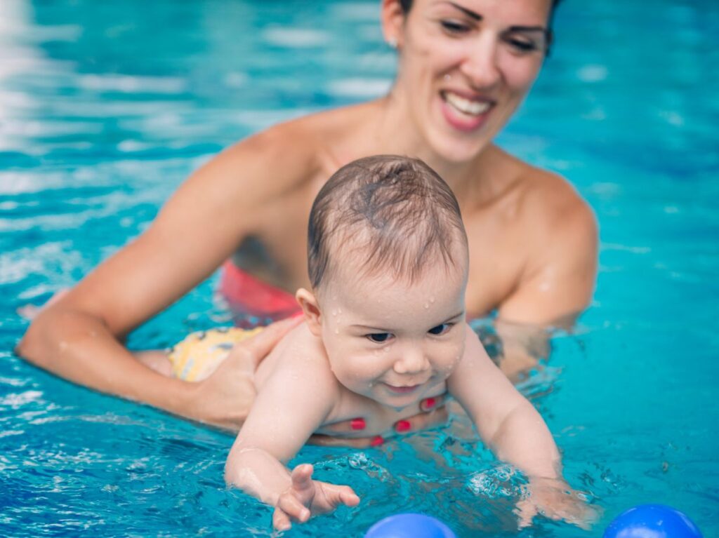 Un bebé tomando una clase de natación para bebés con papás