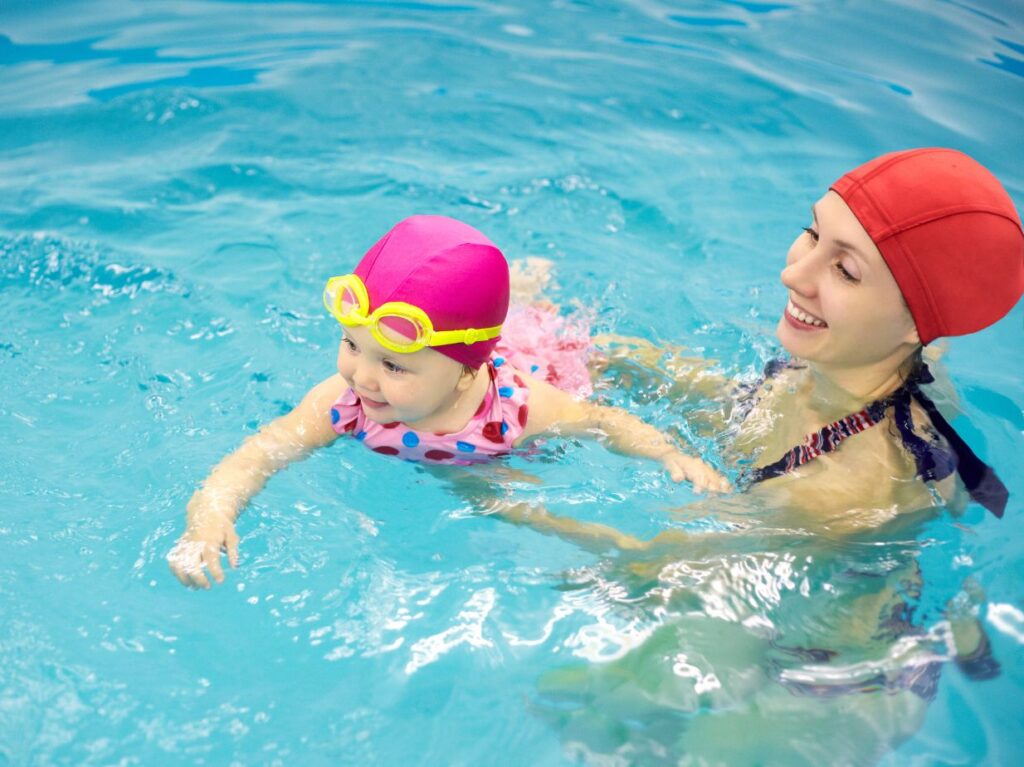 Una mamá que se pregunta qué considerar antes de inscribir a mi bebé a clases de natación, nadando con su bebé en una alberca
