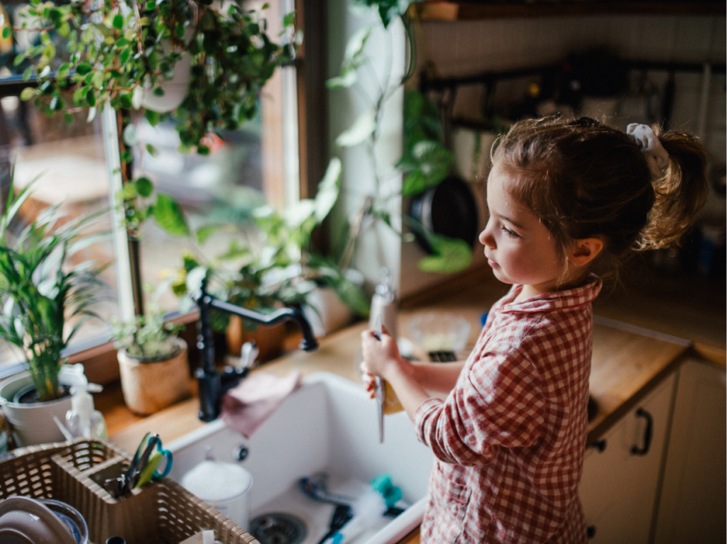 Una niña con autonomía lavando trastes