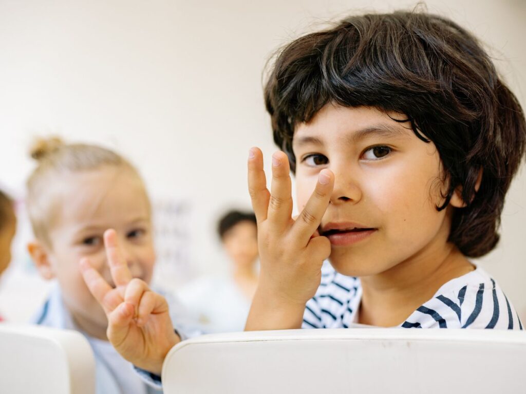 Un niño introvertido haciendo una señal de tres con la mano