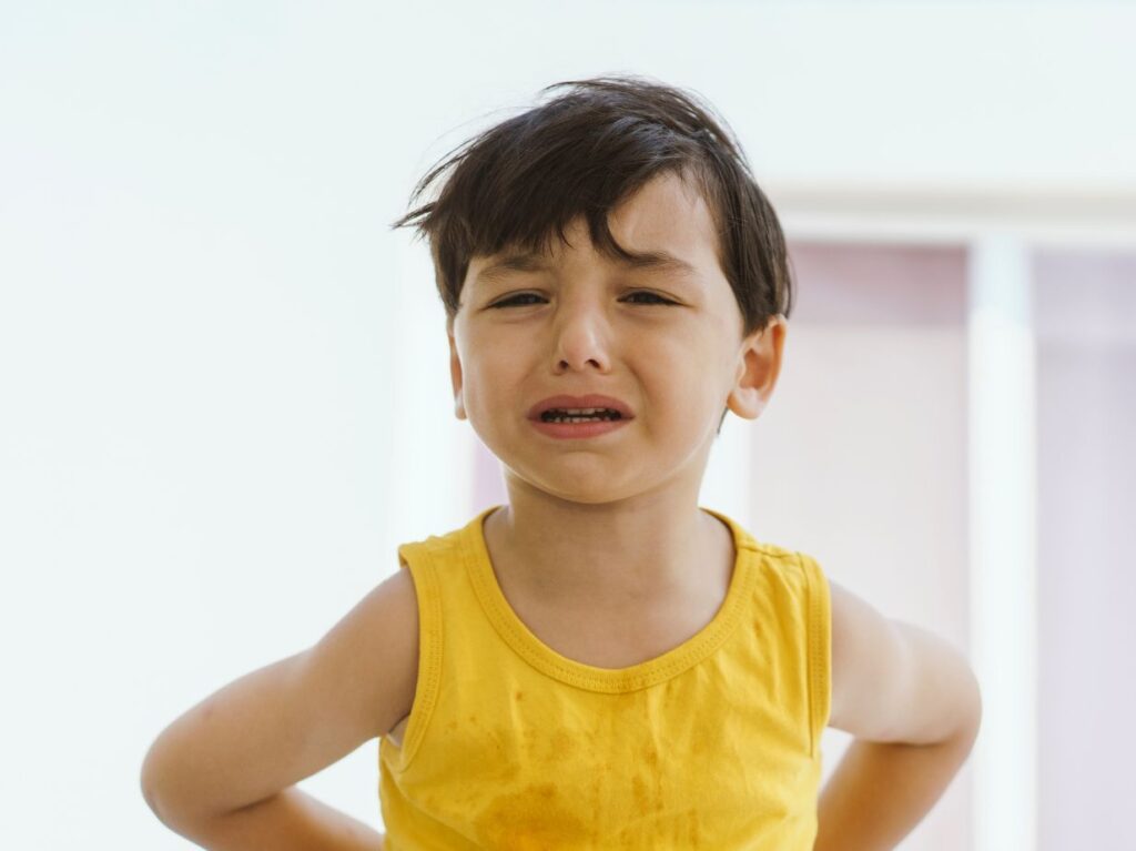 Un niño llorando desconsoladamente, con camiseta amarilla