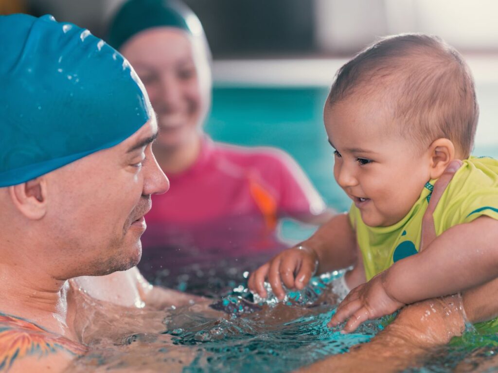 Papá nadando con su bebé. Un papá que sabe cómo elegir la mejor escuela de natación