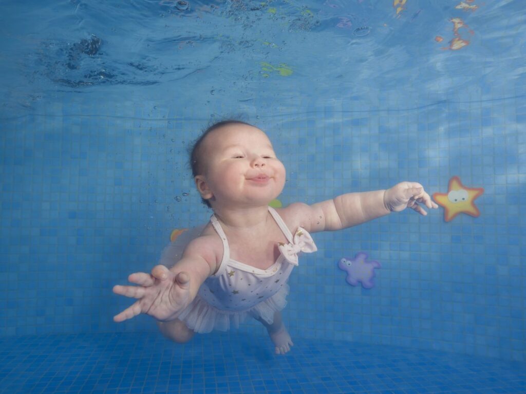 Beba nadando bajo el agua, aguantando la respiración 